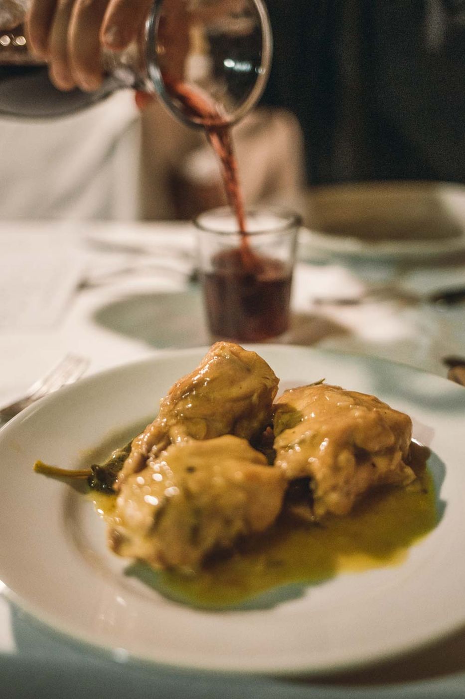 Coniglio al vino bianco, con vino versato nel bicchiere sullo sfondo