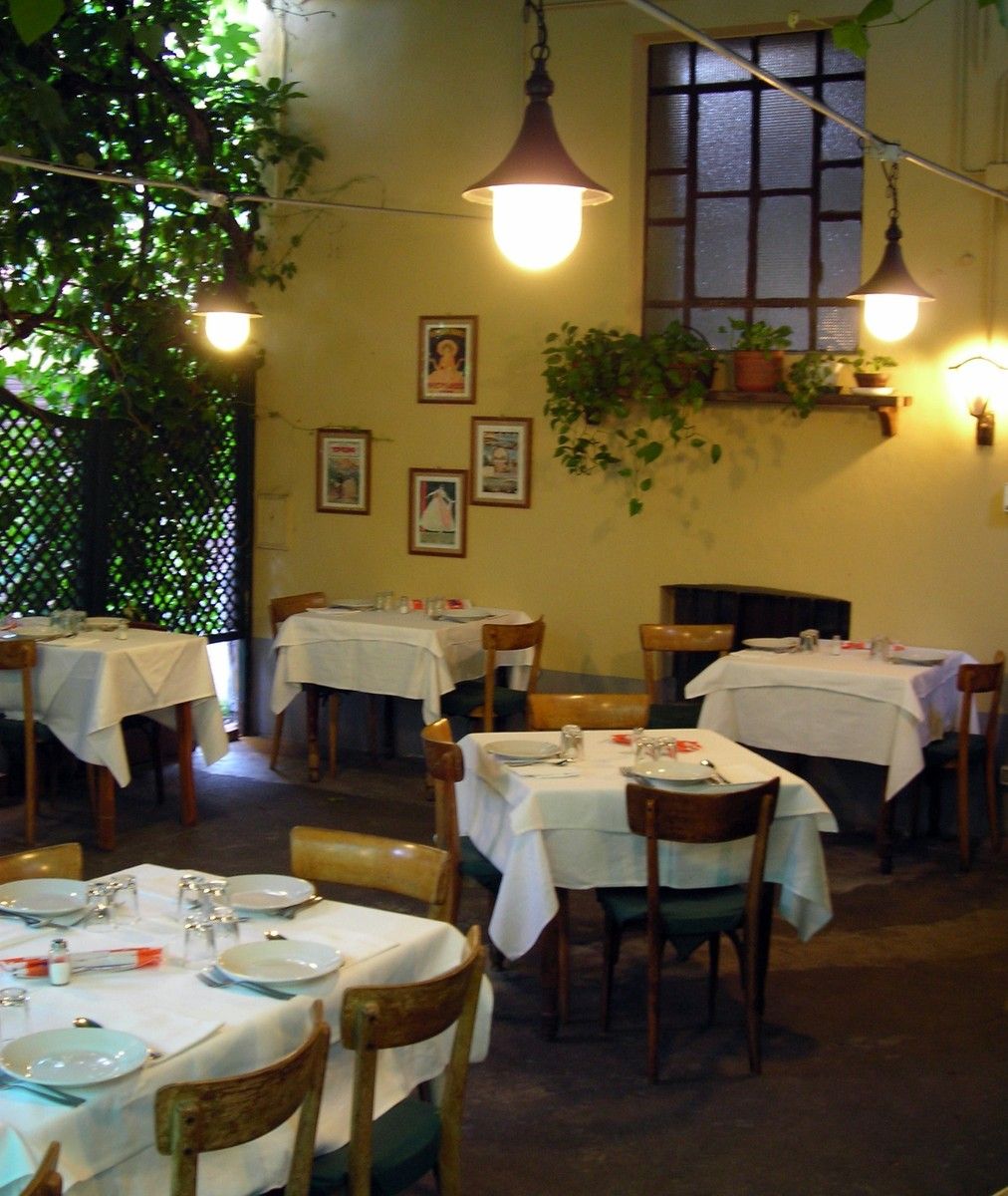 Il cortile estivo sotto il pergolato di vite, con lampade e tavoli apparecchiati