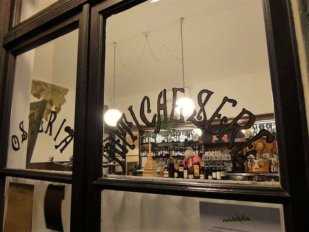 La vetrina con la scritta «Osteria Antiche Sere» e il banco del bar sullo sfondo